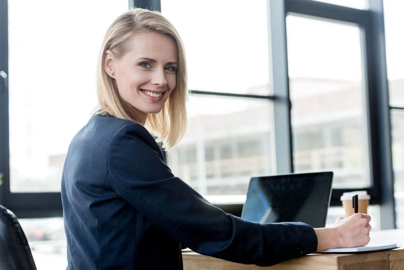 Woman in a suit sling while on her laptop learning how to use lenovo ThinkSmart hub. 